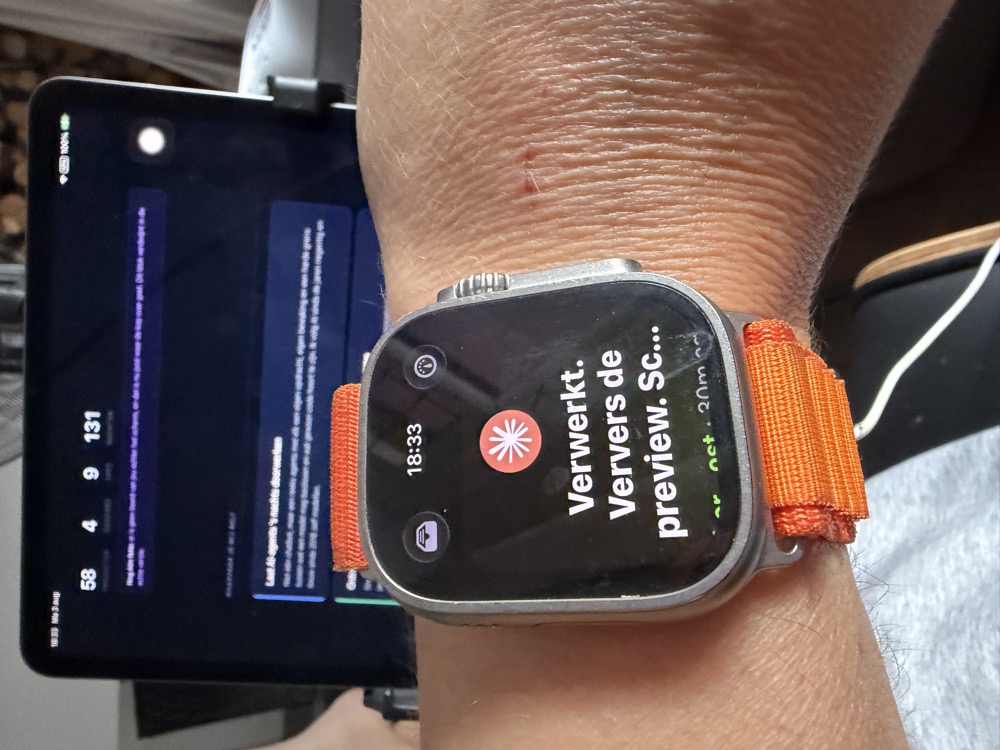 Apple Watch met een melding dat er werk klaar is, ervoor een iPad met het resultaat